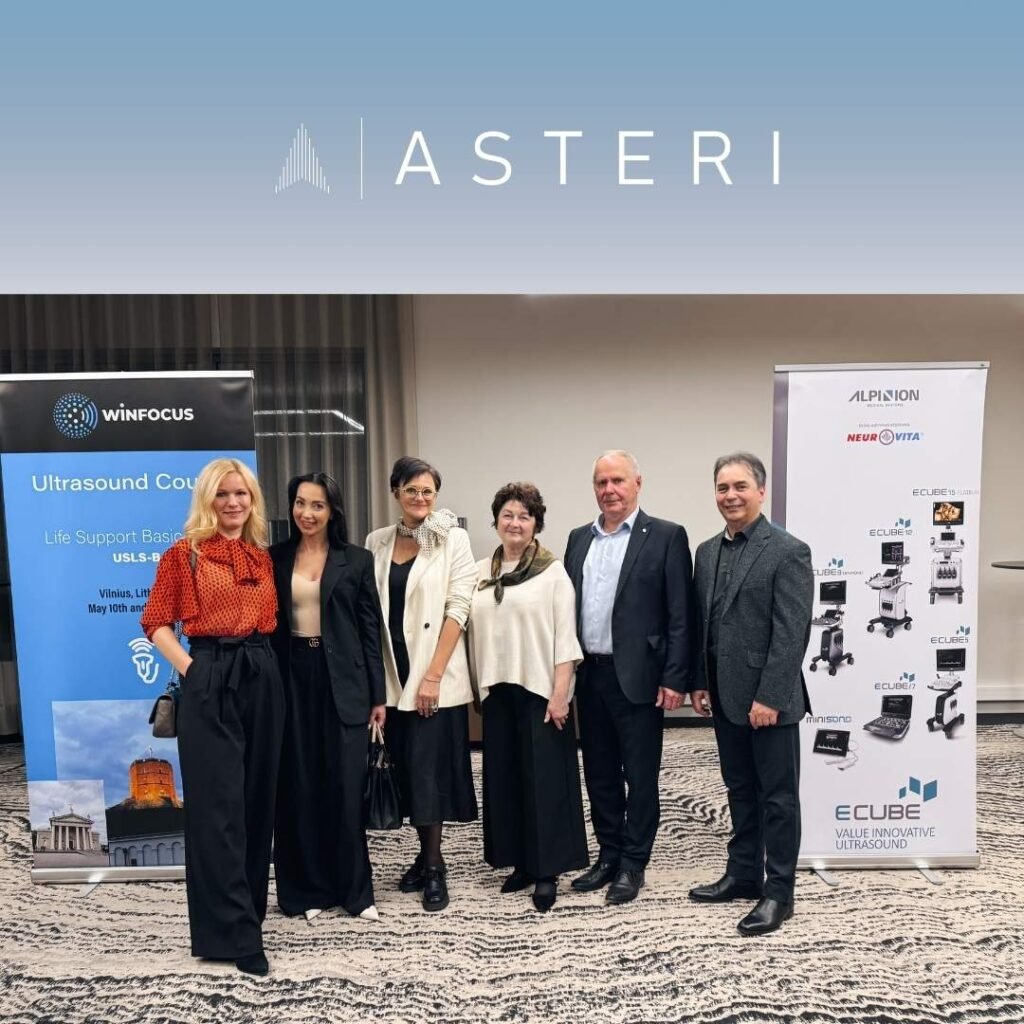 Grupinė nuotrauka iš pirmojo WINFOCUS Baltic kurso priėmimo Vilniuje – renginio dalyviai, tarp jų Asteri vadovė Joana Šaulienė, stovi prie informacinių stendų apie ultragarso mokymus